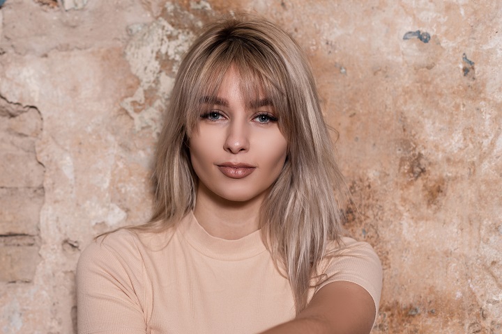 Curtain bangs. Modna grzywka 2025. Na zdjęciu blondynka z długimi włosami i curtain bangs