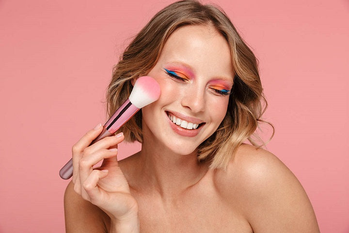 Jak wykonać makijaż mineralny uśmiechnięta dziewczyna z pędzlem w dłoni
